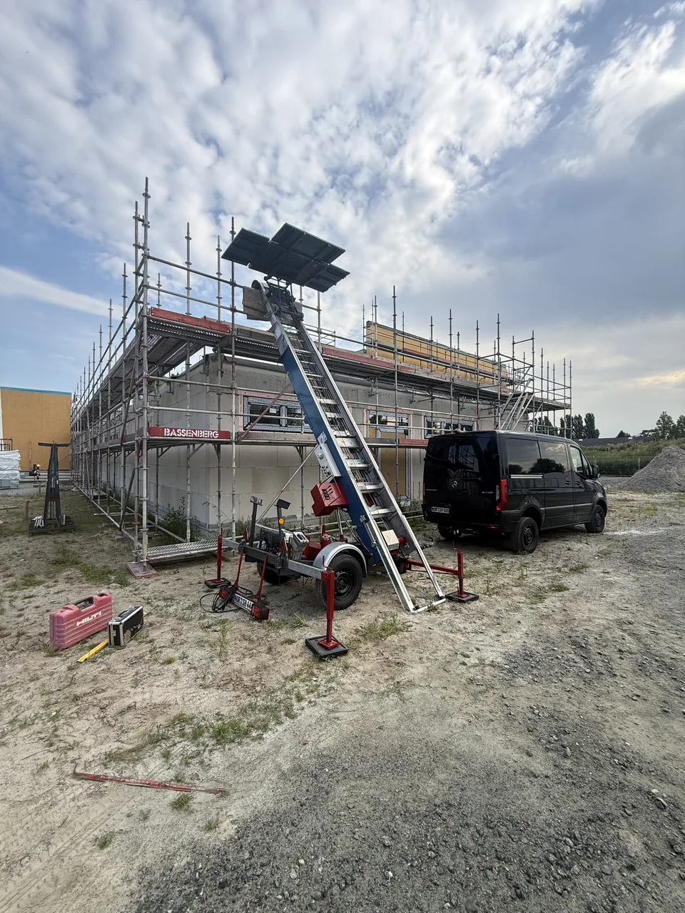 Herzig Dienstleistungen: Außenlift vor einem eingerüsteten Gebäude beim Materialtransport.