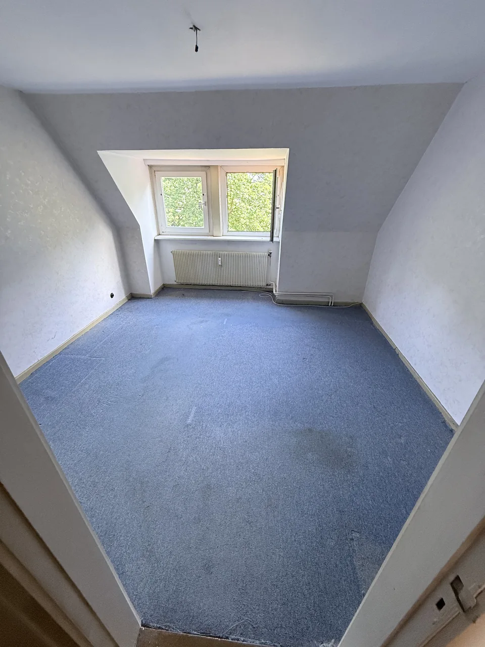 Herzig Dienstleistungen: Das geräumte Dachzimmer mit blauem Boden und freiem Zugang zum Fenster.
