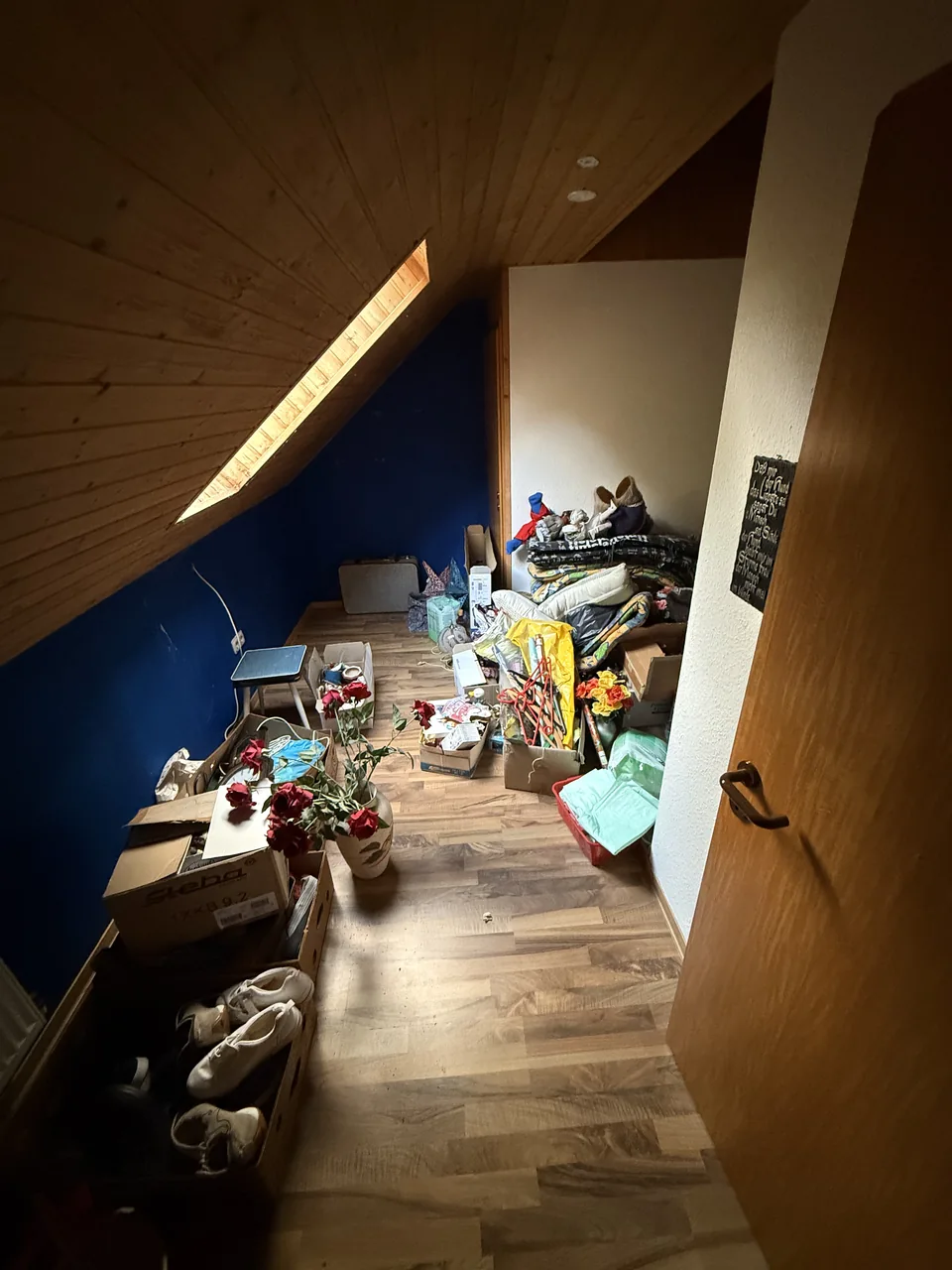 Herzig Dienstleistungen: Hausrat und Möbel im Dachgeschoss mit Holzdecke und blauer Wand.