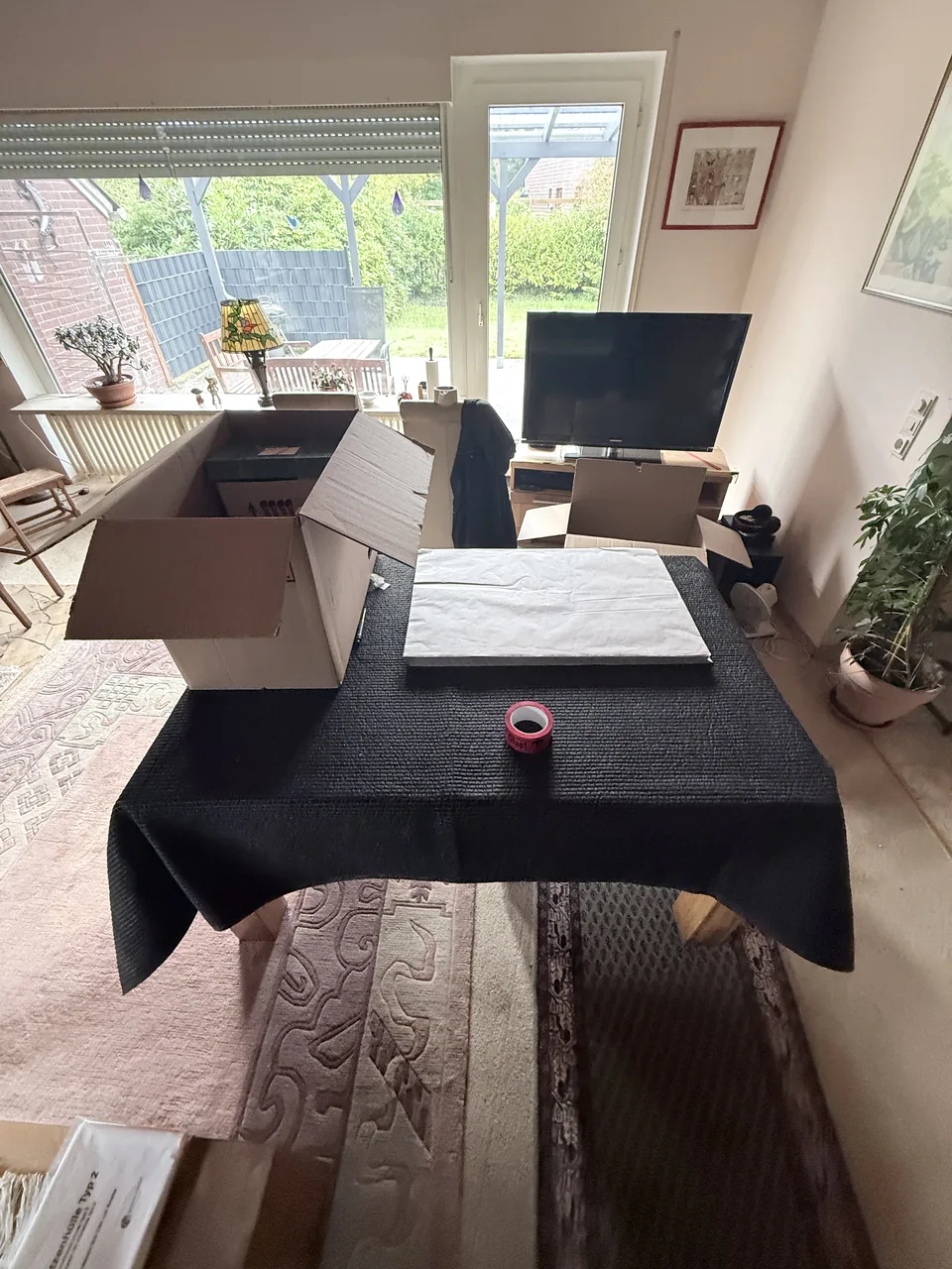 Herzig Dienstleistungen: Umzugskartons und Verpackungsmaterial auf einer Schutzdecke im Wohnbereich.