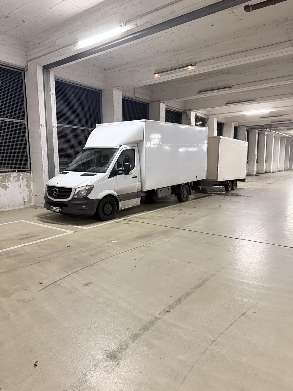 Herzig Dienstleistungen: Transporter und Kofferanhänger in einer großen Halle.