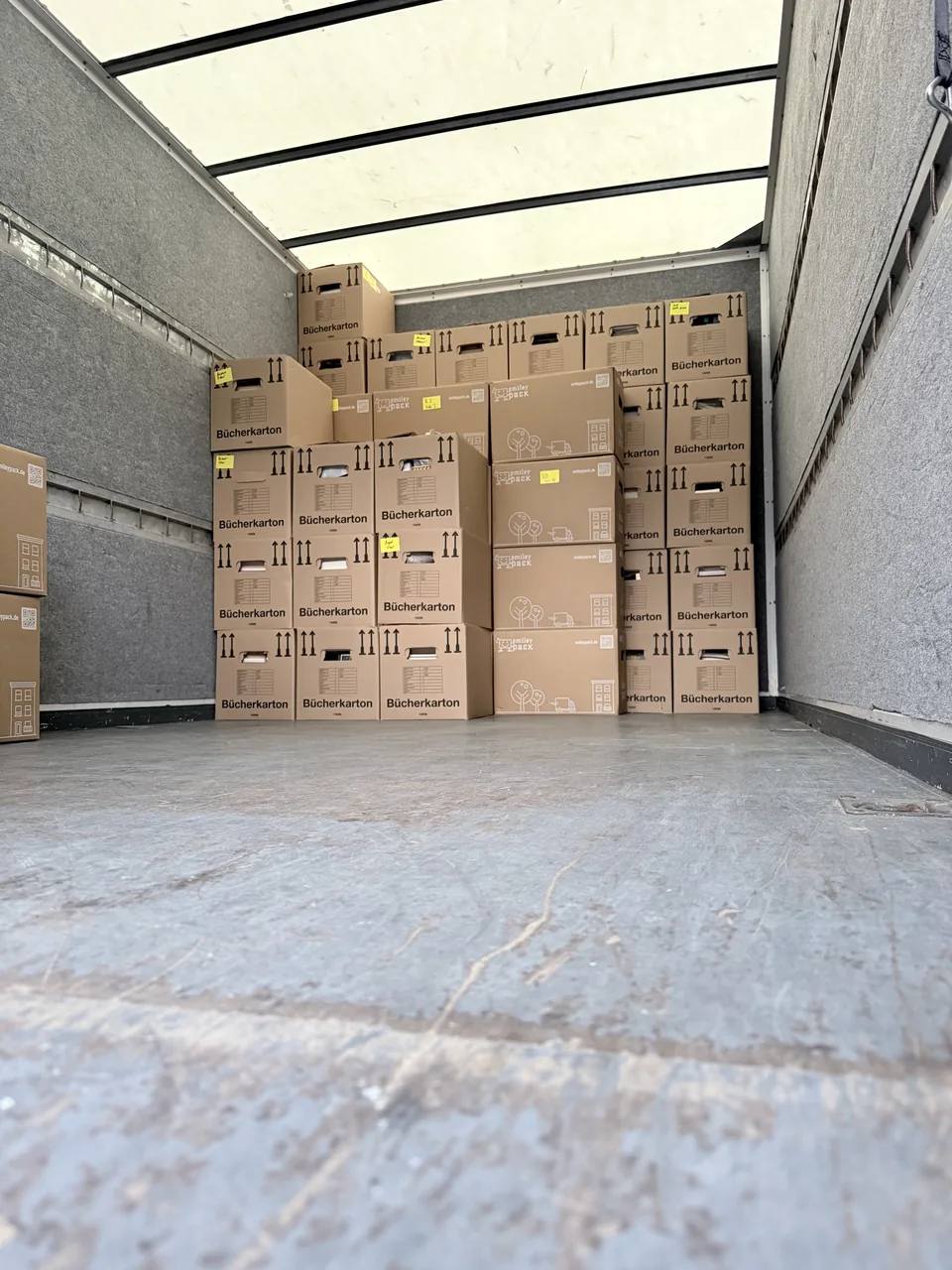Herzig Dienstleistungen: Umzugskartons stehen gestapelt im Laderaum des Möbeltransporters.