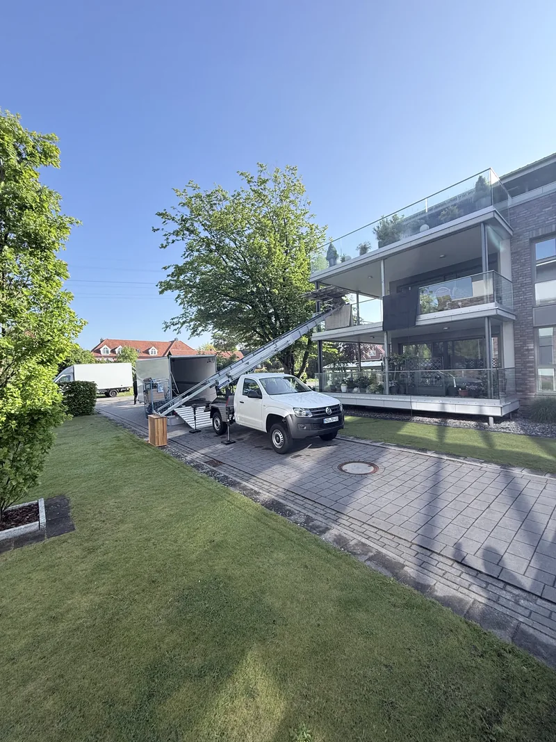 Möbellift von Herzig auf einem weißen VW Amarok beim Umzug über den Balkon eines Wohnhauses