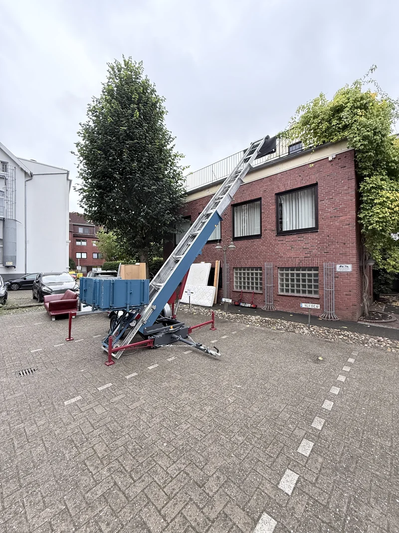 Anhänger-Möbellift an einem Backsteingebäude mit Dachterrasse