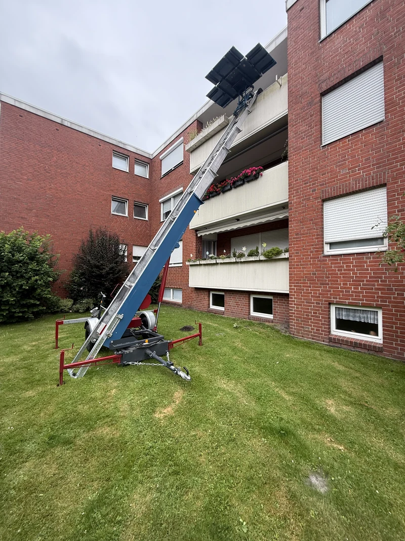 Anhänger-Möbellift im Einsatz an einem Balkon eines Mehrfamilienhauses