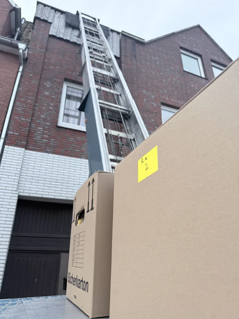 Umzugskartons auf der Liftplattform vor einem Wohnhaus
